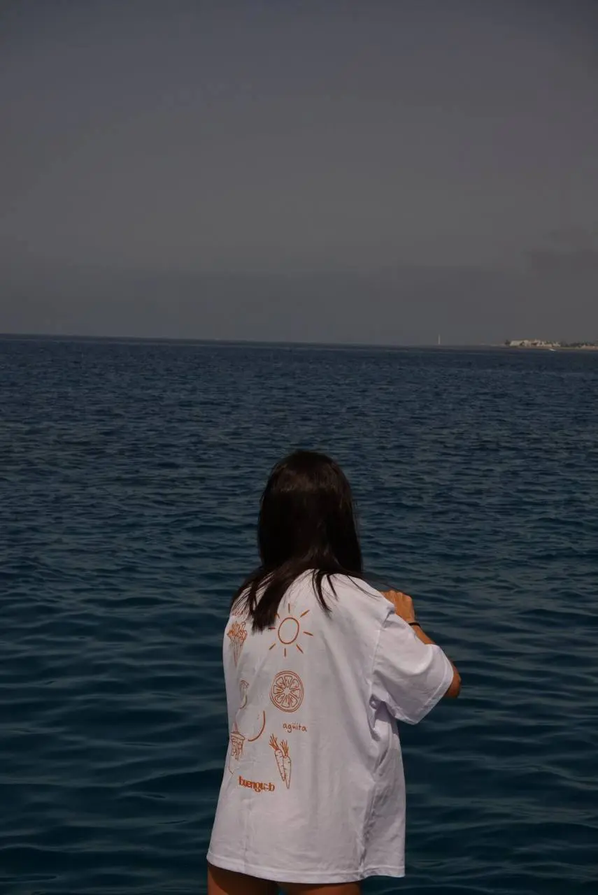 Camiseta de BuengustoLab vista por detrás junto al mar, con una ilustración de gran formato