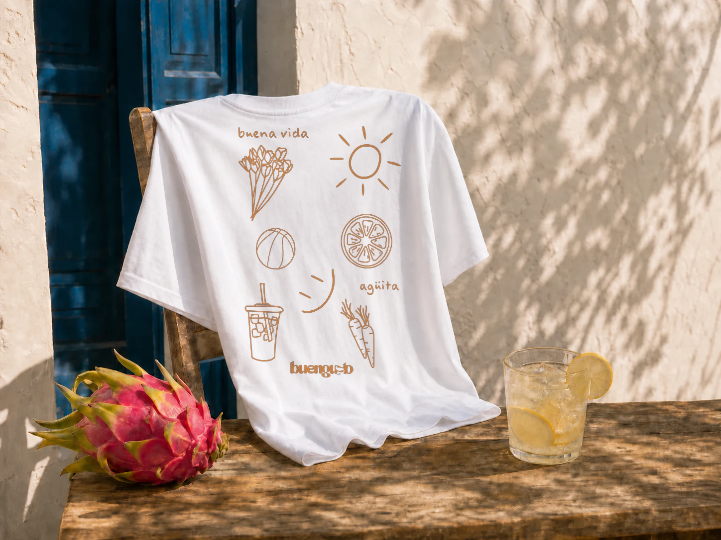 Composición editorial de la camiseta BuengustoLab por detrás sobre una silla, con el estampado trasero original, pitaya y limonada